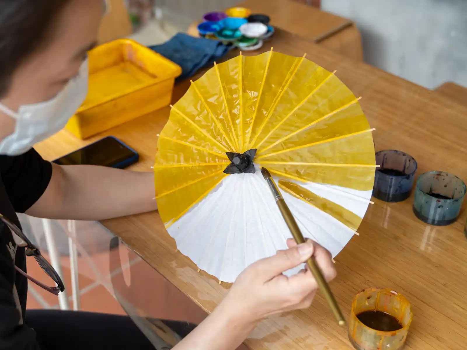 A tourist carefully hand paints her own custom oil-paper umbrella.