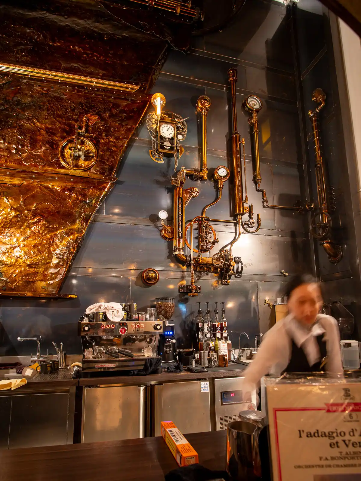 Industrial pipes and gadgets decorate the rear wall behind the counter.