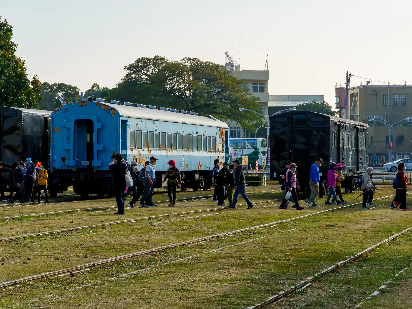 Tourists walk among parked traincars and take photos.