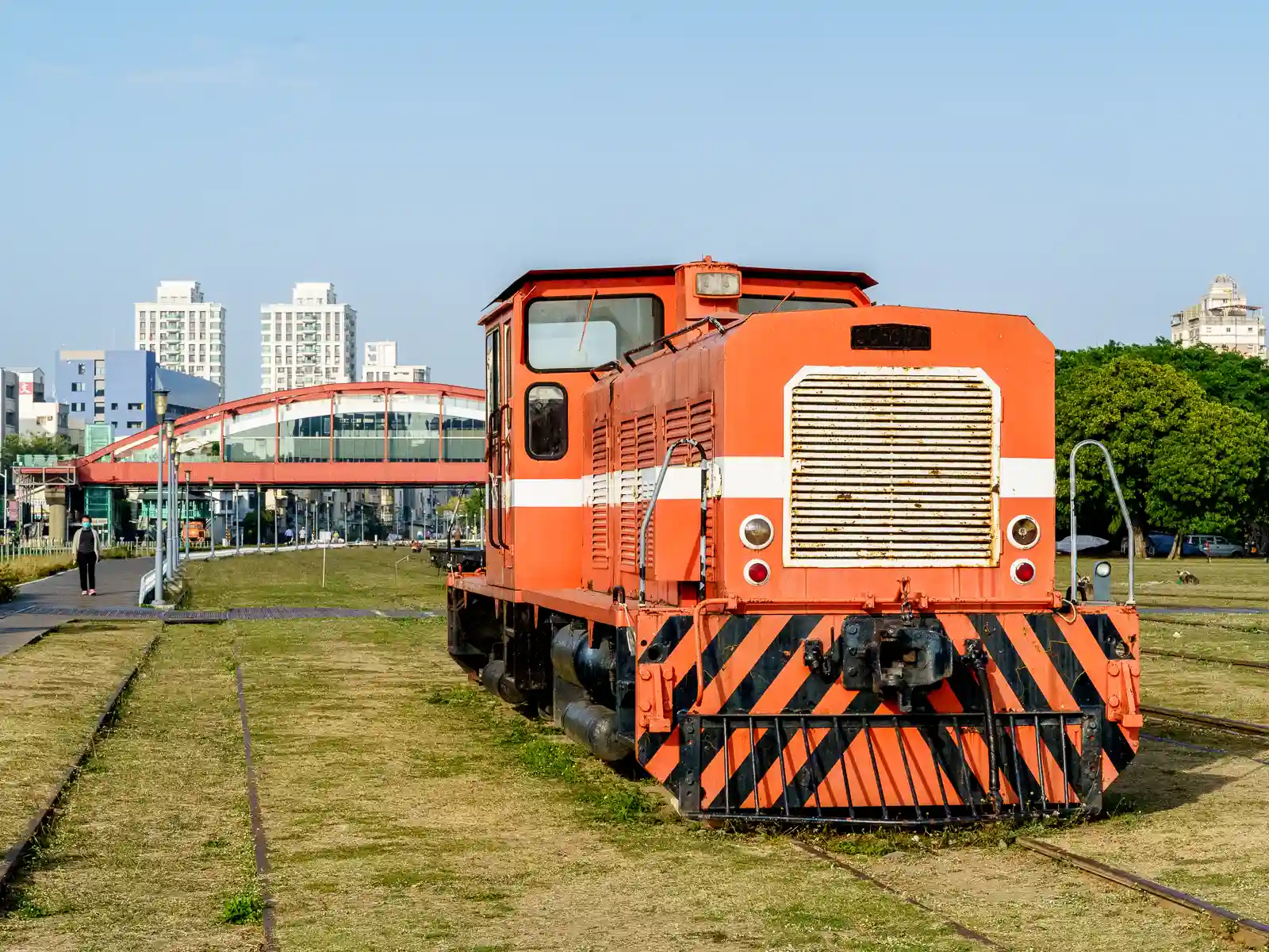 An orange locomotive stands on display surrounded by empty train tracks.