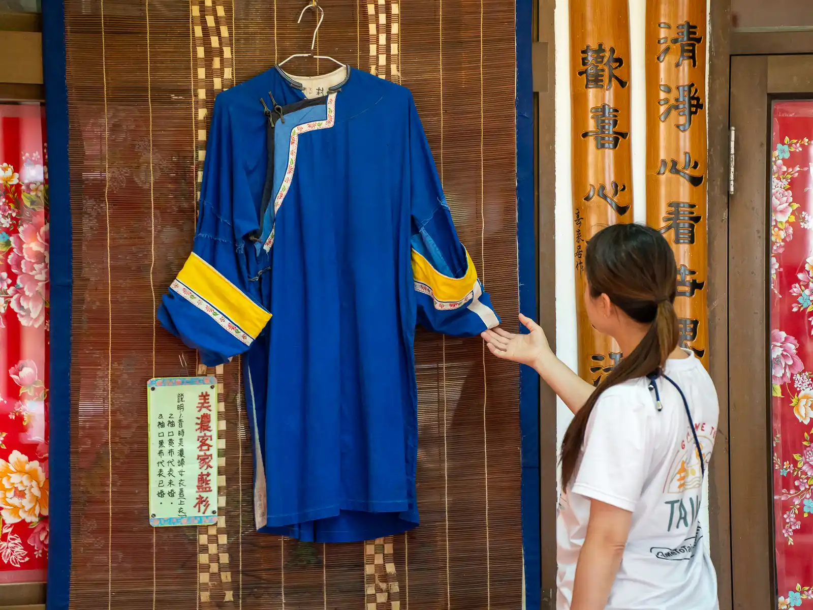 A Hakka blue shirt is displayed hanging on a wall.