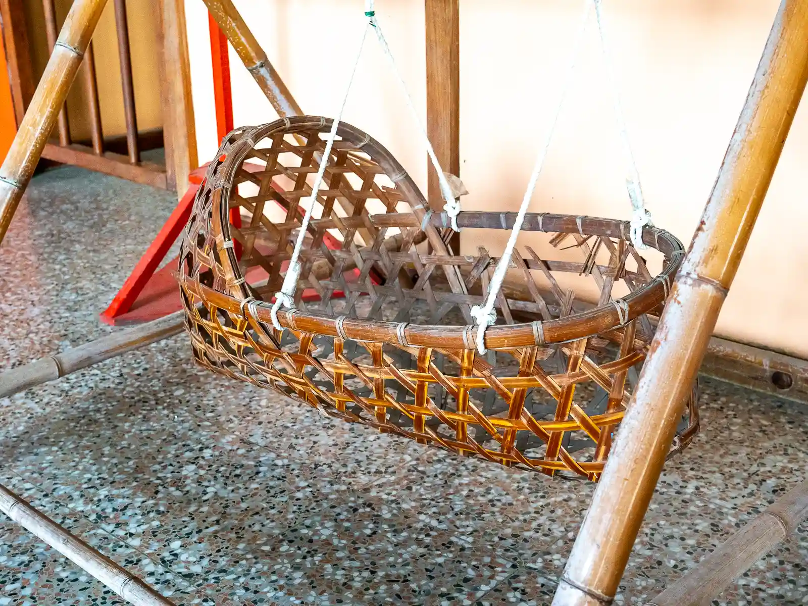 A cradle for a baby made from rattan is on display.