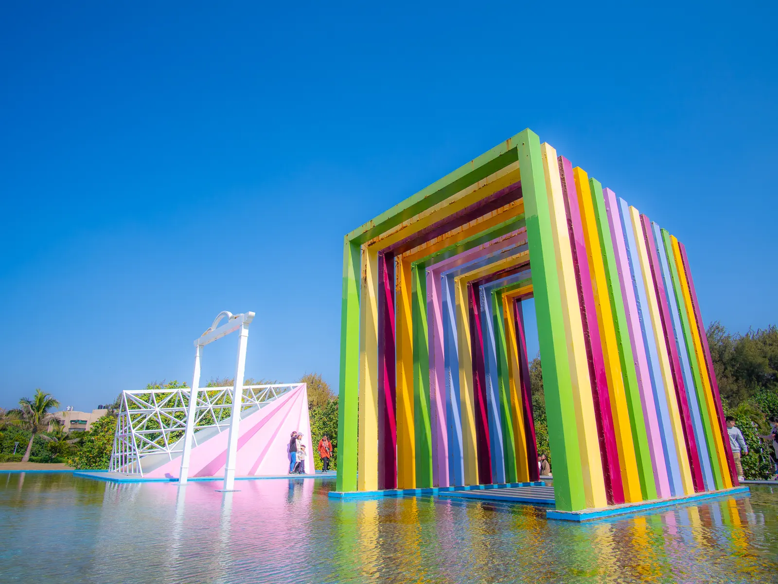 The Rainbow Church is composed of 13 colored rectangular arches that sit above a shallow pool of water.