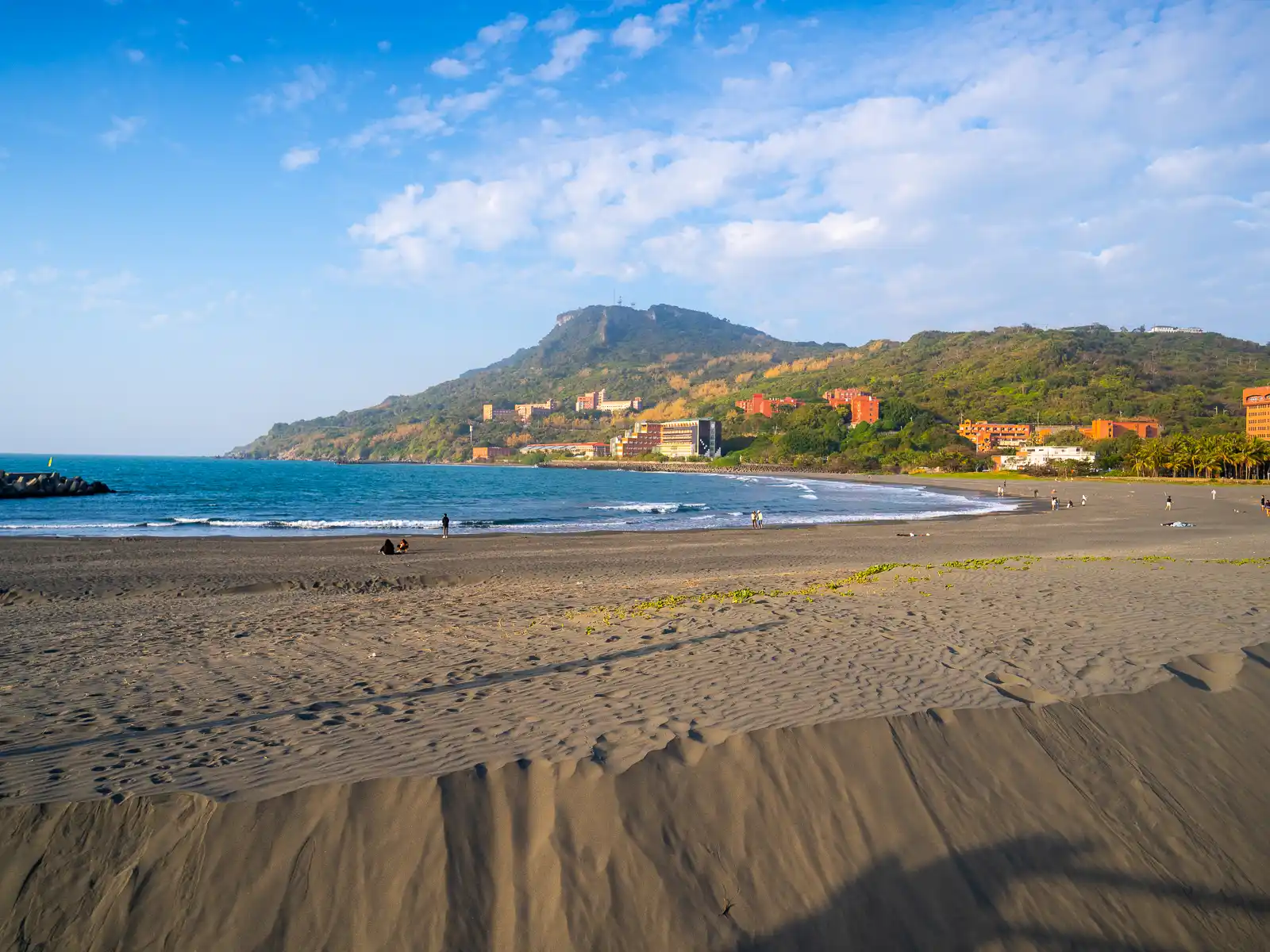 Shoushan Mountain can be seen at the far end of a sandy beach.