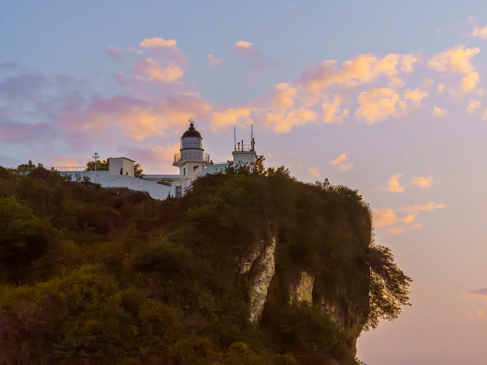 The Kaohsiung Lighthouse can be seen on a cliff during sunset.