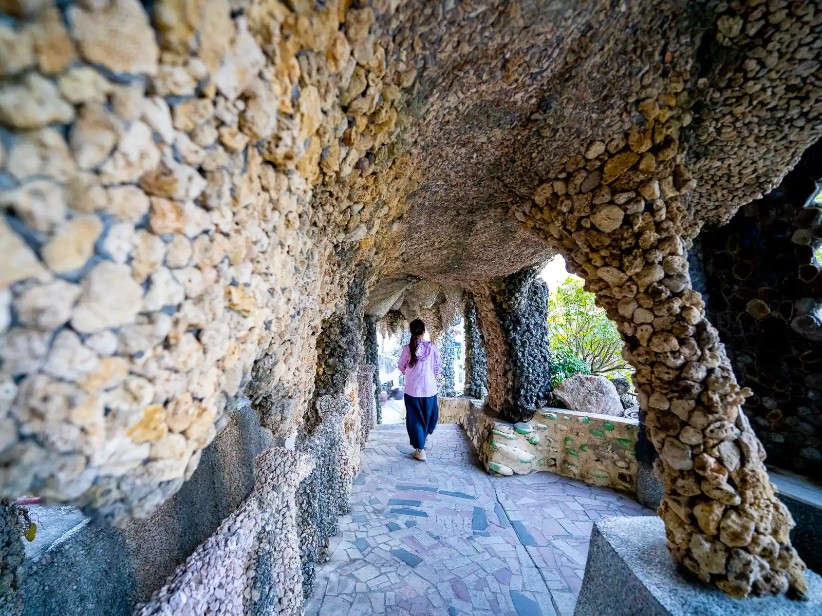 A tourist walks through an arcade constructed of small fist-size pieces of coral.