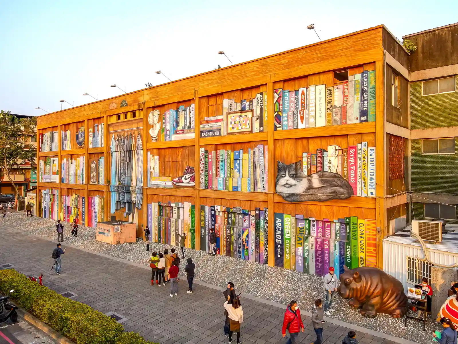 A three-story building is completely decorated with a colorful mural depicting a gigantic library of books.