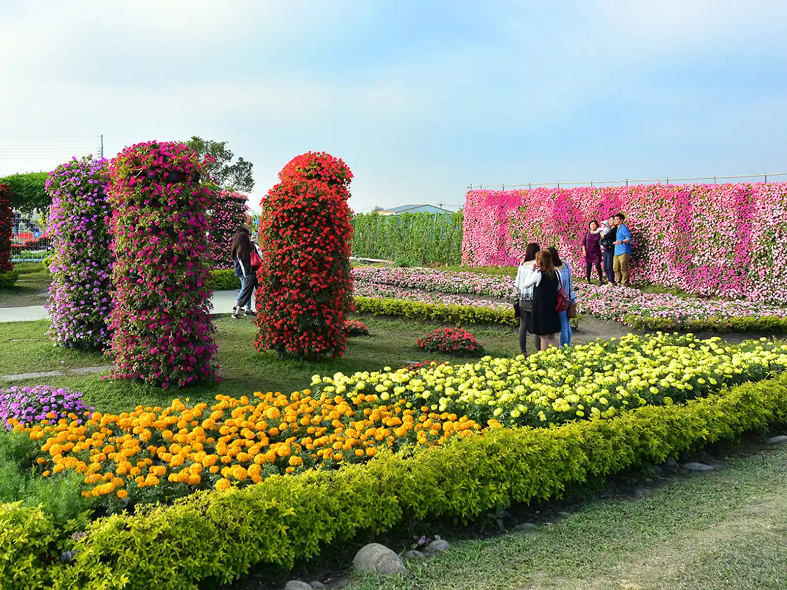 Visitors pose in front of a wall of flowers.
