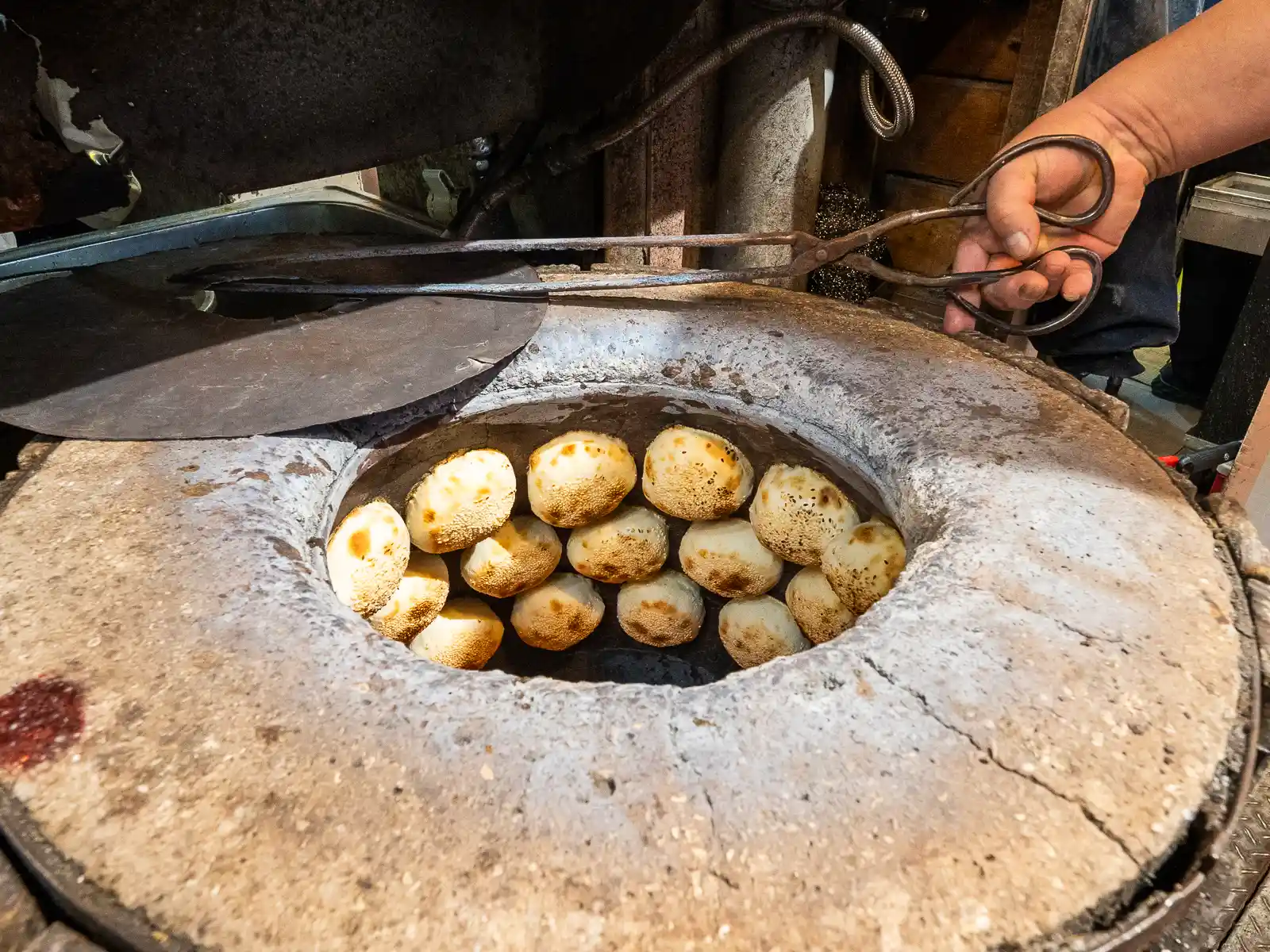Oven-baked black pepper buns are cooking in a stone oven on the street.