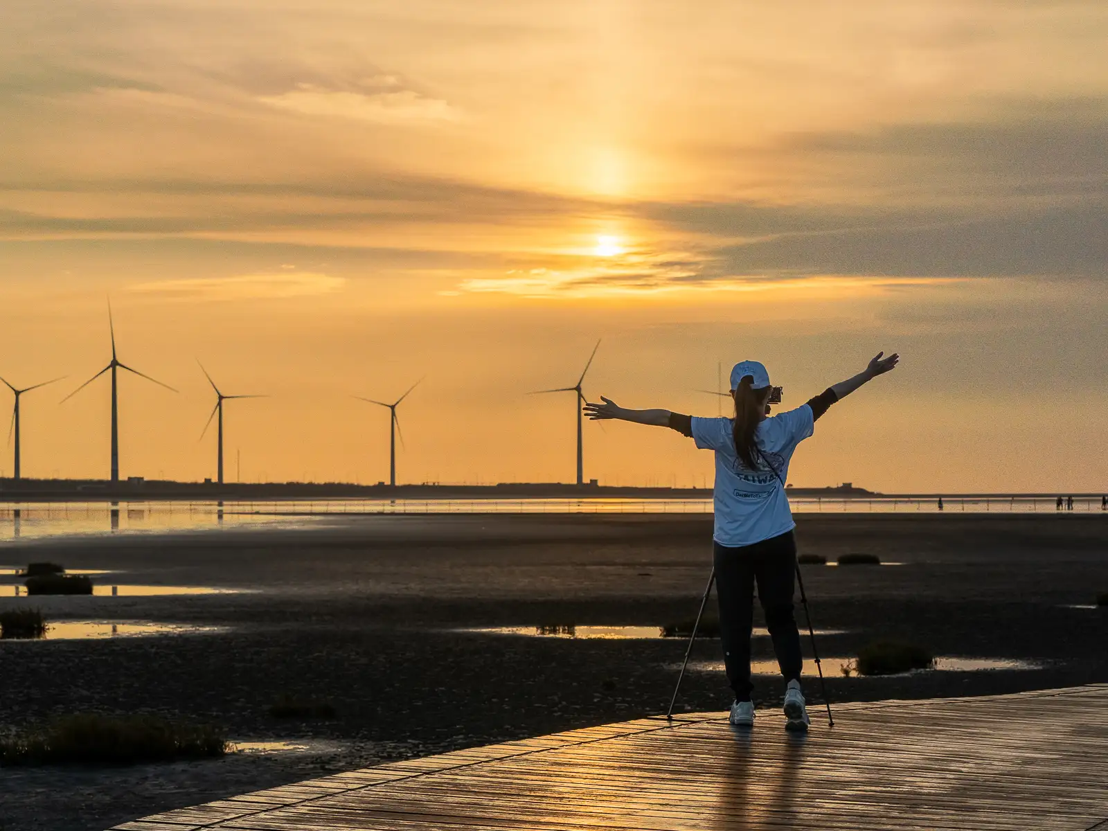 A tourist watches the sun slowly set over the tidal flats of the Gaomei Wetlands.
