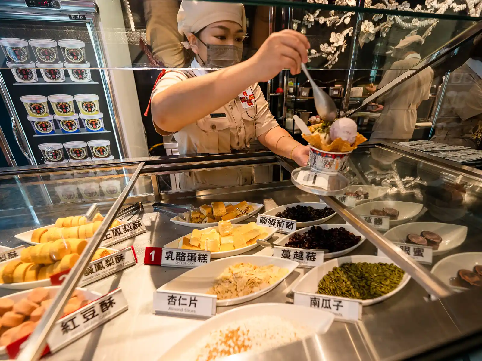 An employee adds toppings to an order of ice cream.
