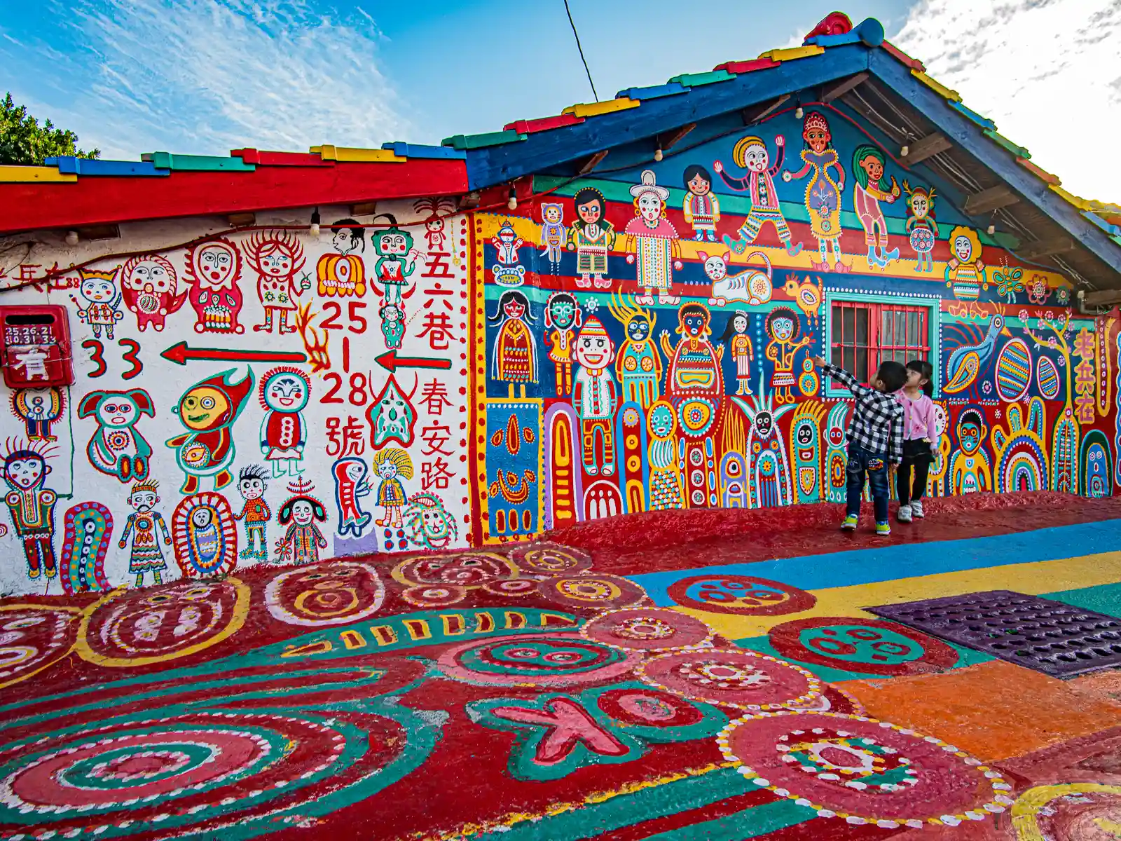 In Taichung’s Rainbow Village, a mural covers everything visible from the roof tiles of a building, to its walls and mailbox, to the cement road surface before it.