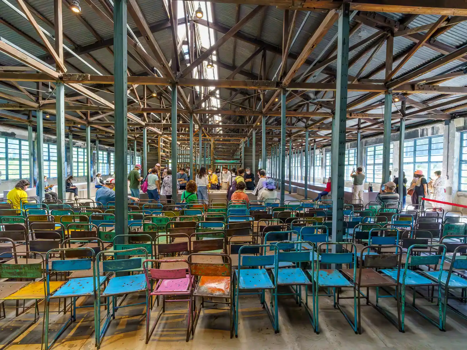 Rows of painted aluminum chairs are placed facing a central table on the airy second floor of the Daxi Tea Factory.
