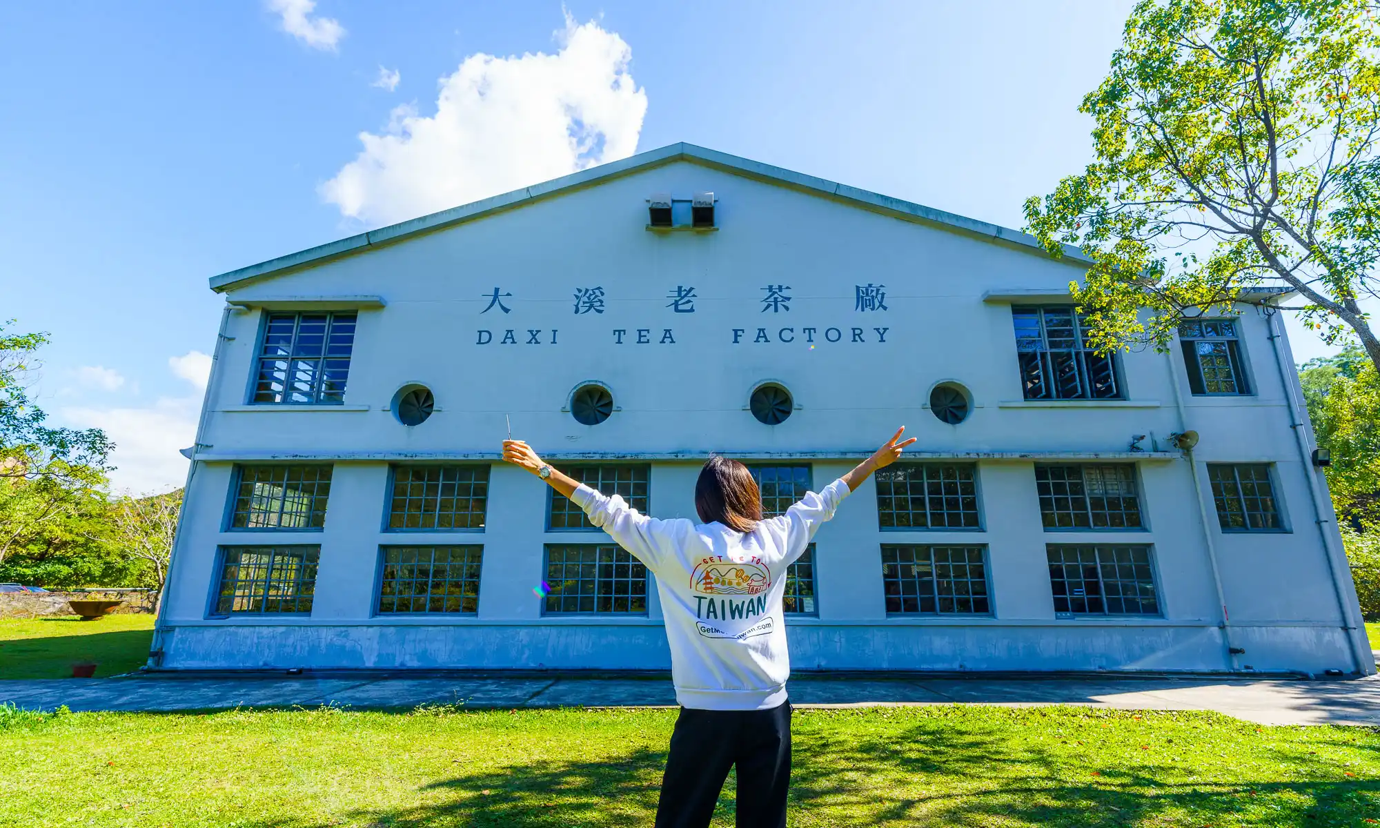 A portrait of a tourist with the Daxi Tea Factory in the background.