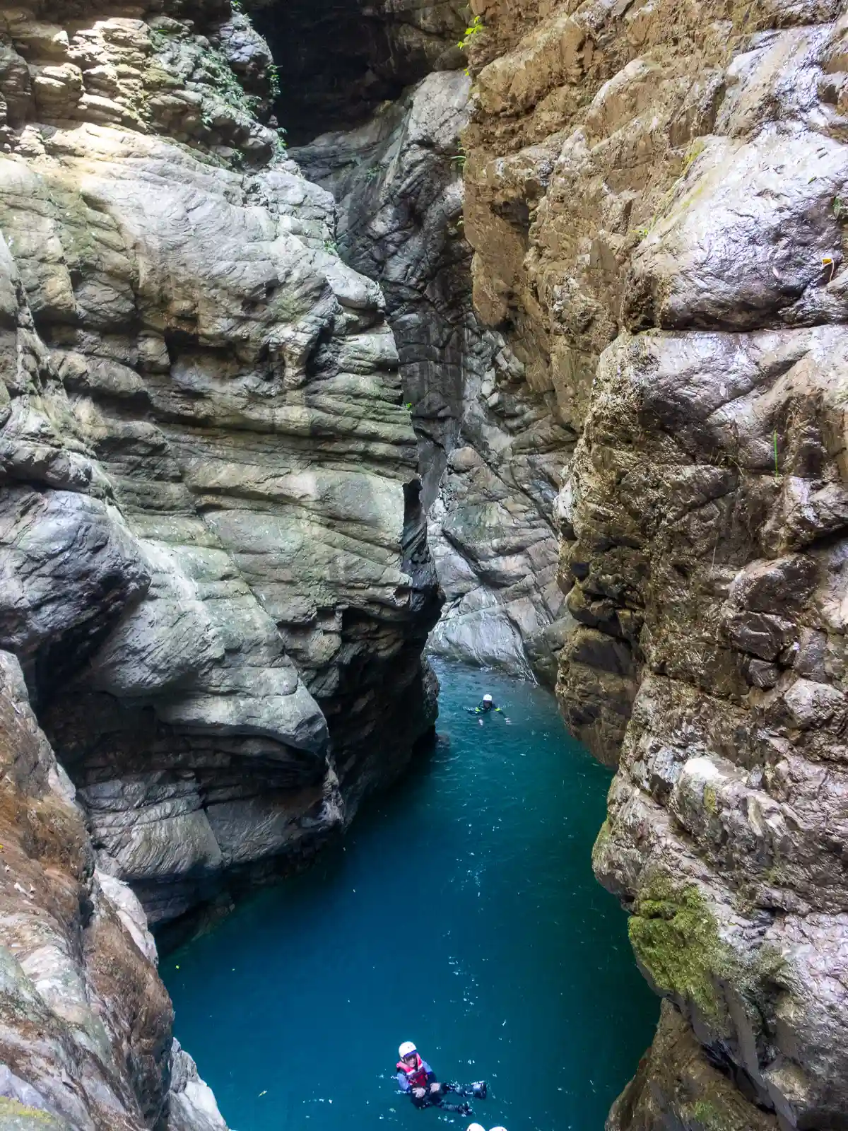 Tourists float in a deep pool surrounded on all sides by canyon walls.