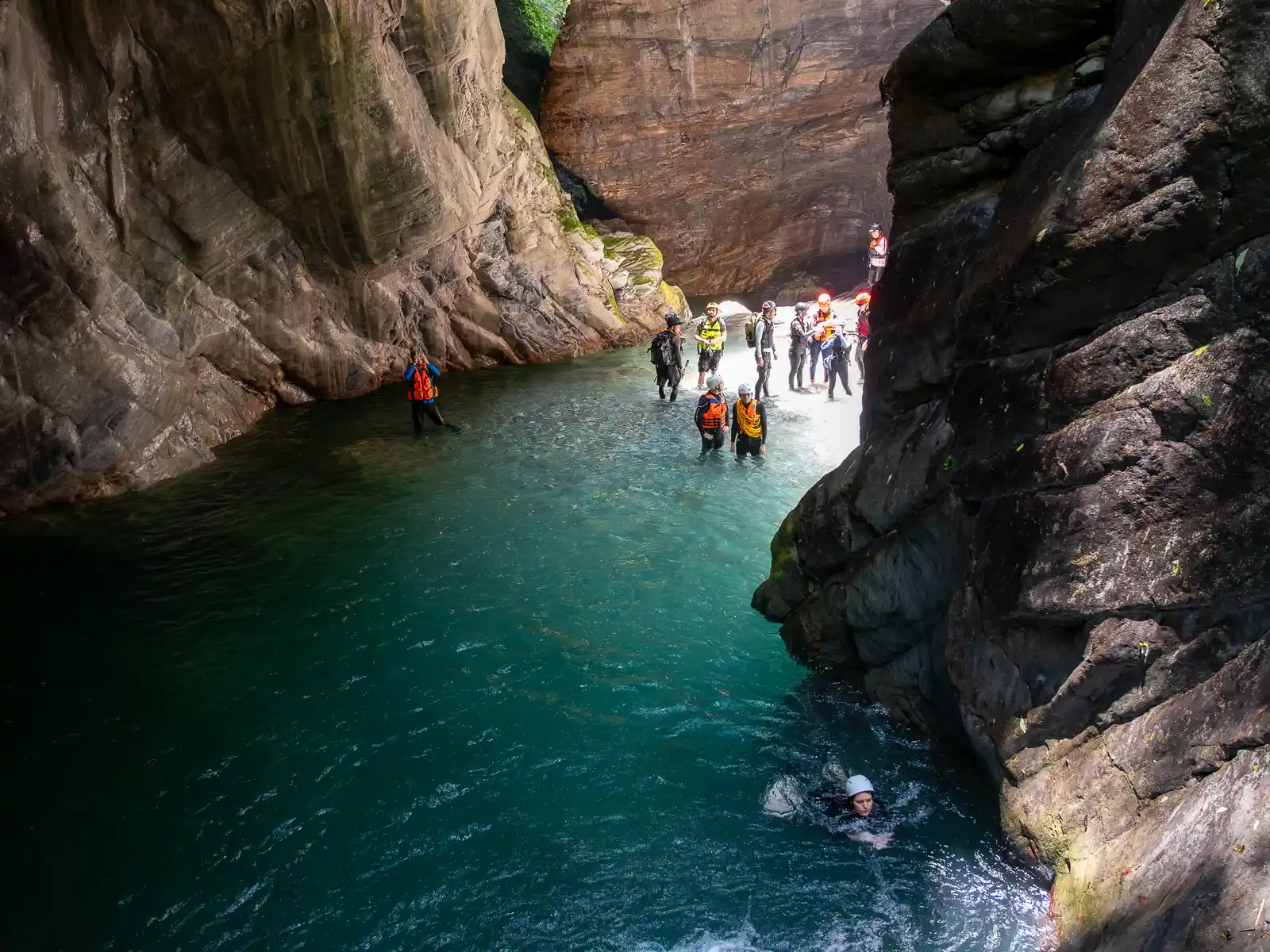 A tour group waits in the swallows end of a pool for their turn to climb.