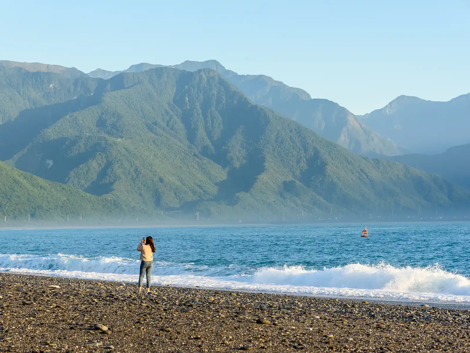 A tourist takes a photo on the shore of Qixing Beach.