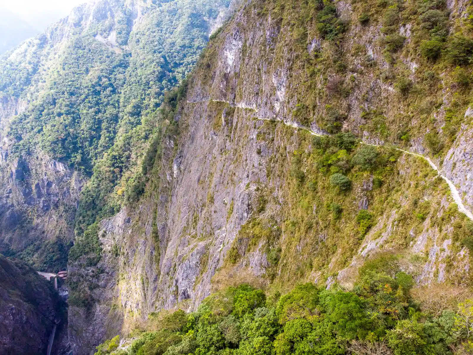 A meter-wide trail can be seen traversing a vertical cliff face.