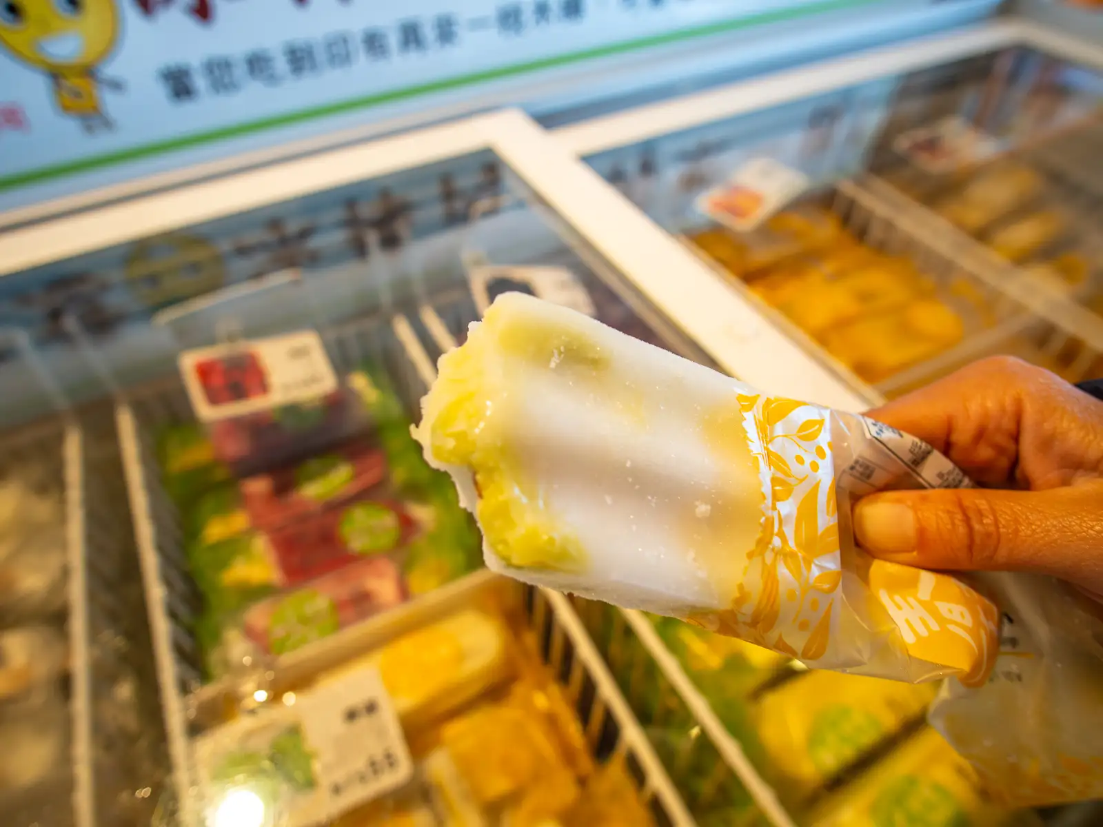 A mango green ice pop with a bite taken out of it.