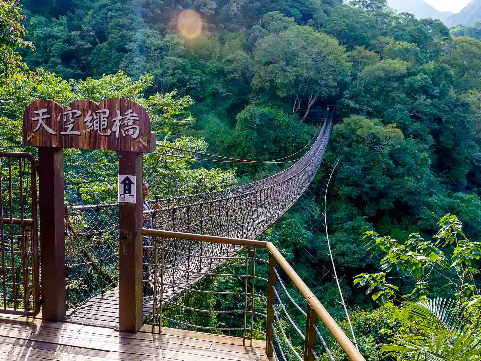 A rope bridge made of rope and wooden plants leads across a long valley.