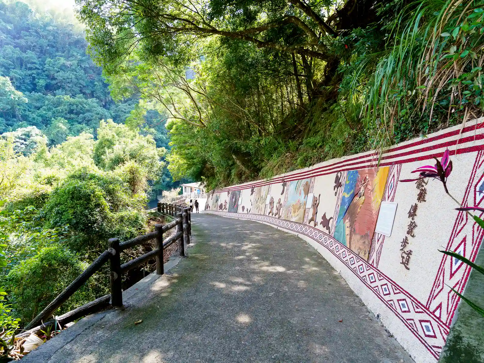 One side of a path leading down a mountainside is decorated with colorful stone reliefs.