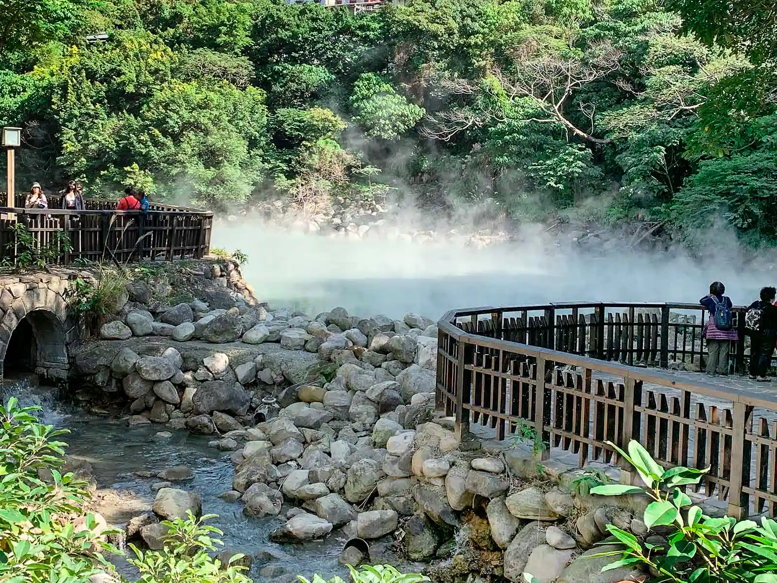 A layer of steam can be seen covering the pool of the Geothermal Valley beyond a viewing platform.