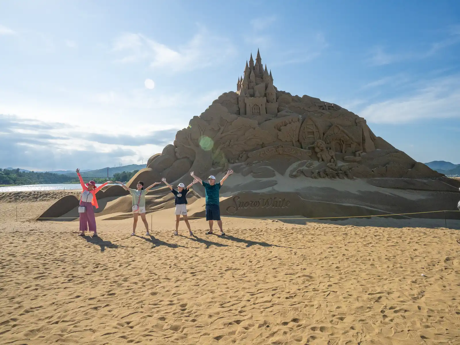 Tourists are posting in front of sand sculpture of Snow White's Castle.
