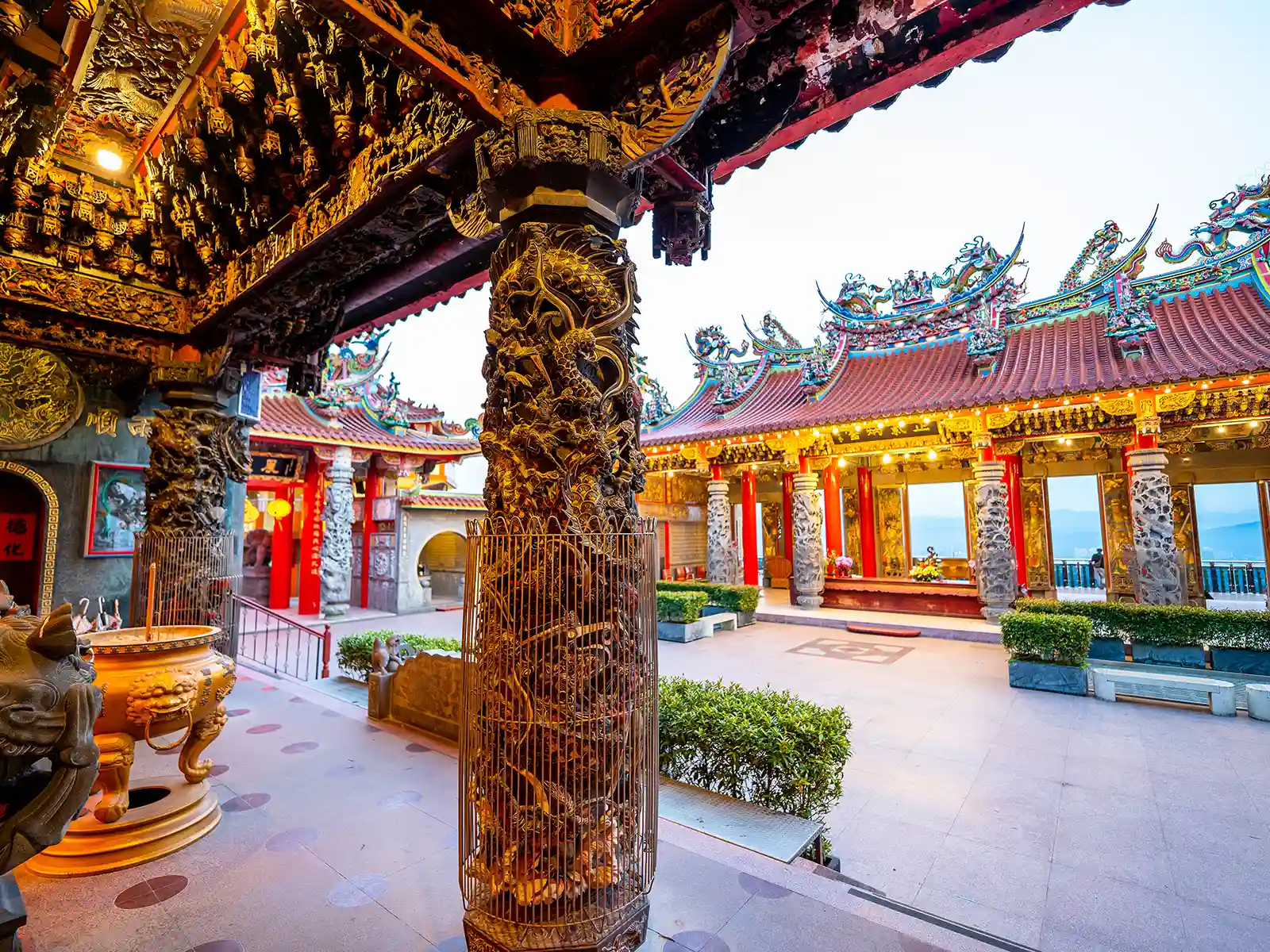 A courtyard in a temple is decorated with carved stone columns, and includes a view onto Taipei Basin.