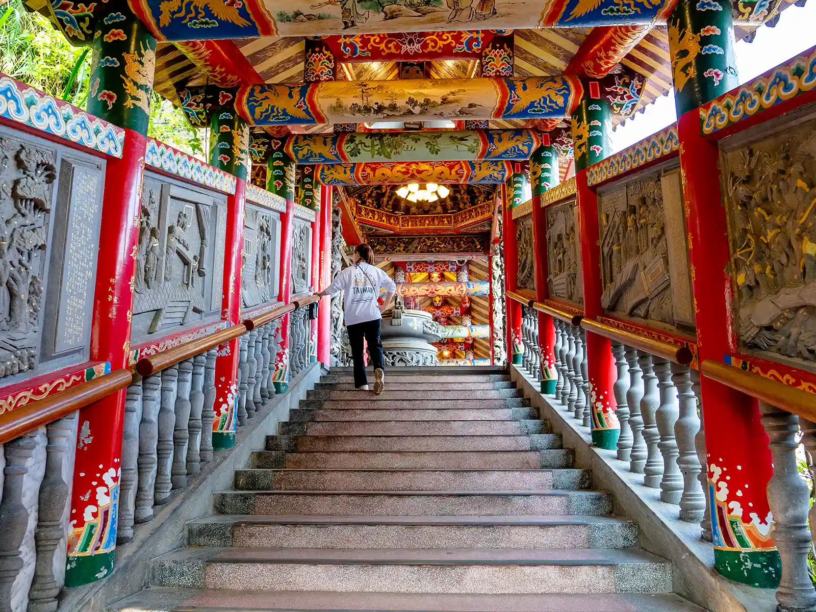 A tourist walks up a beautifully decorated multicolored staircase.