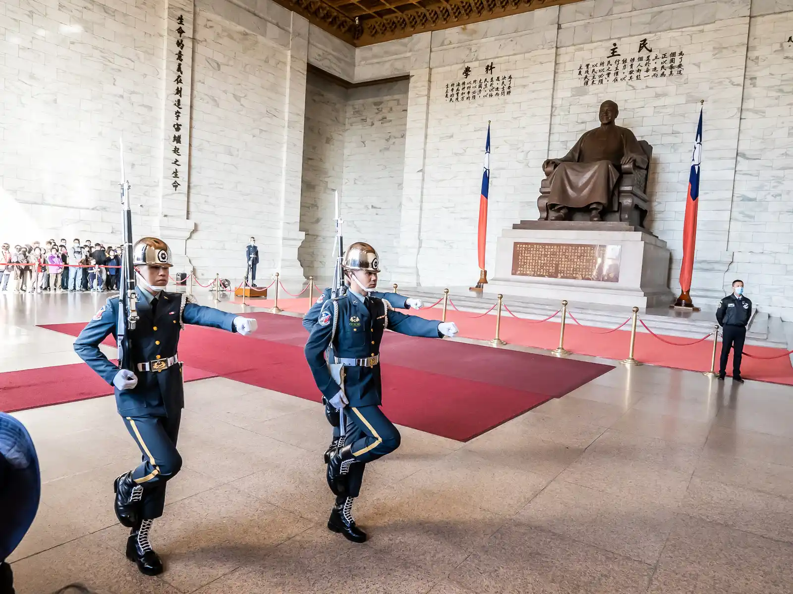 Three guards marching in front of the multi-story statue of Chiang Kai Shek.