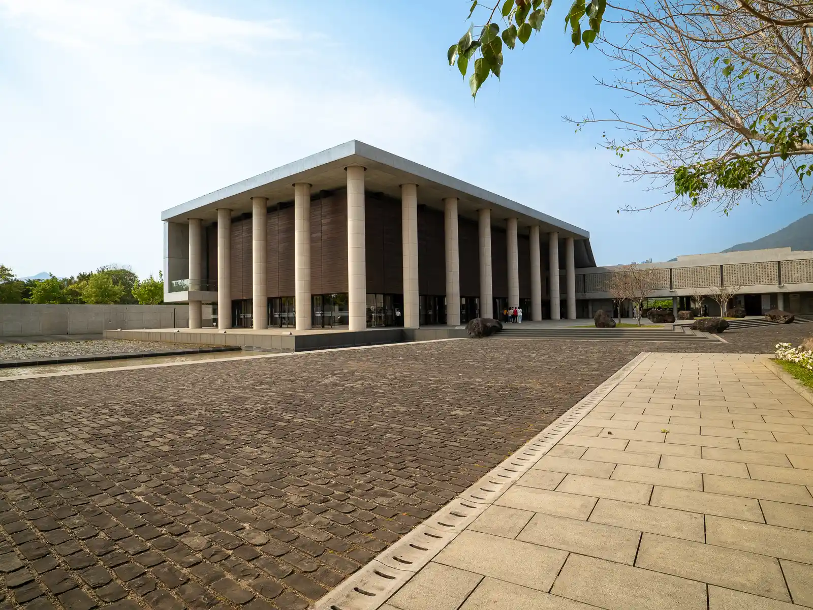 The temple's modern main hall with pillars and a clear sky.