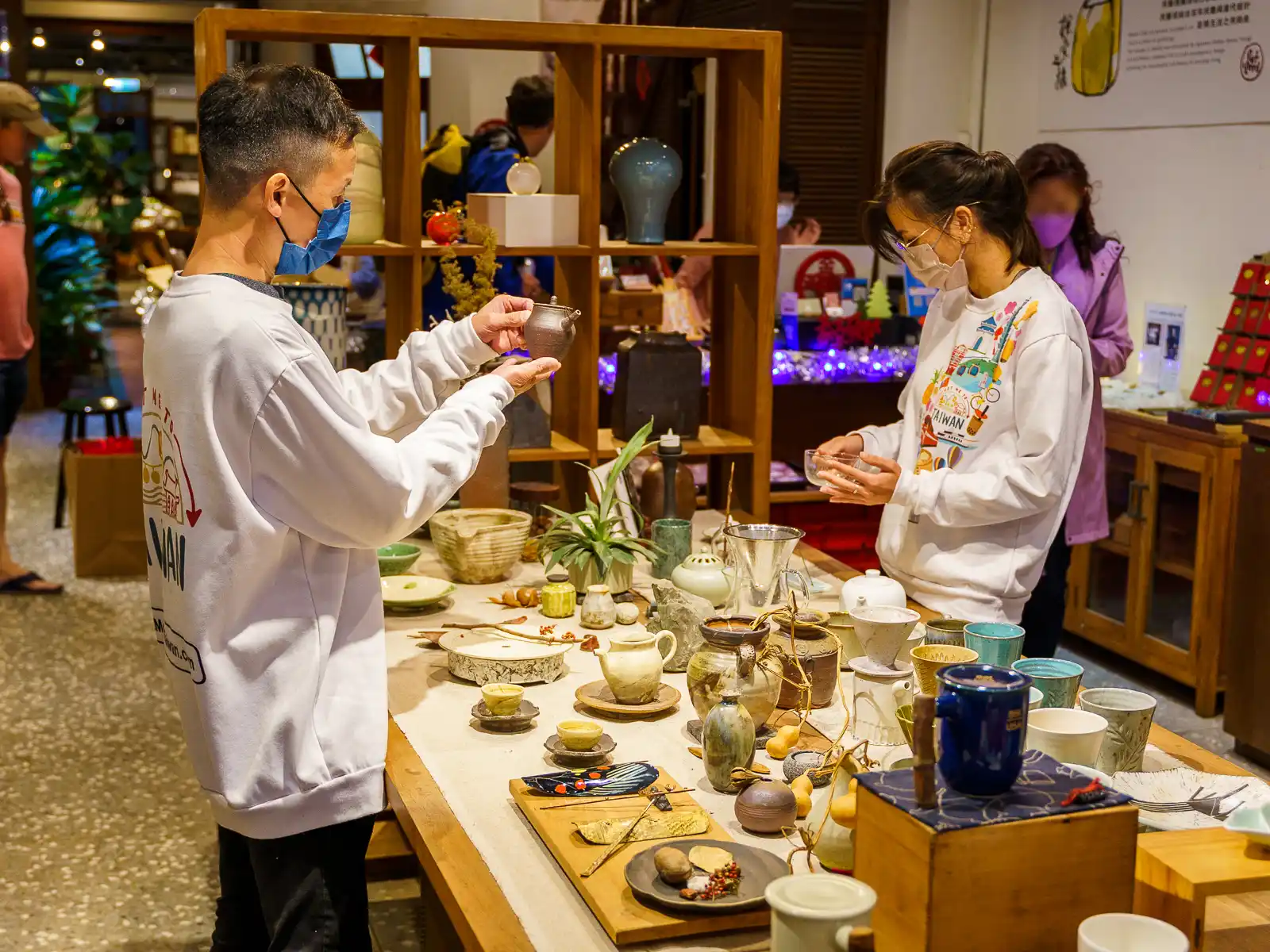 Two people examining designer pottery in a shop.