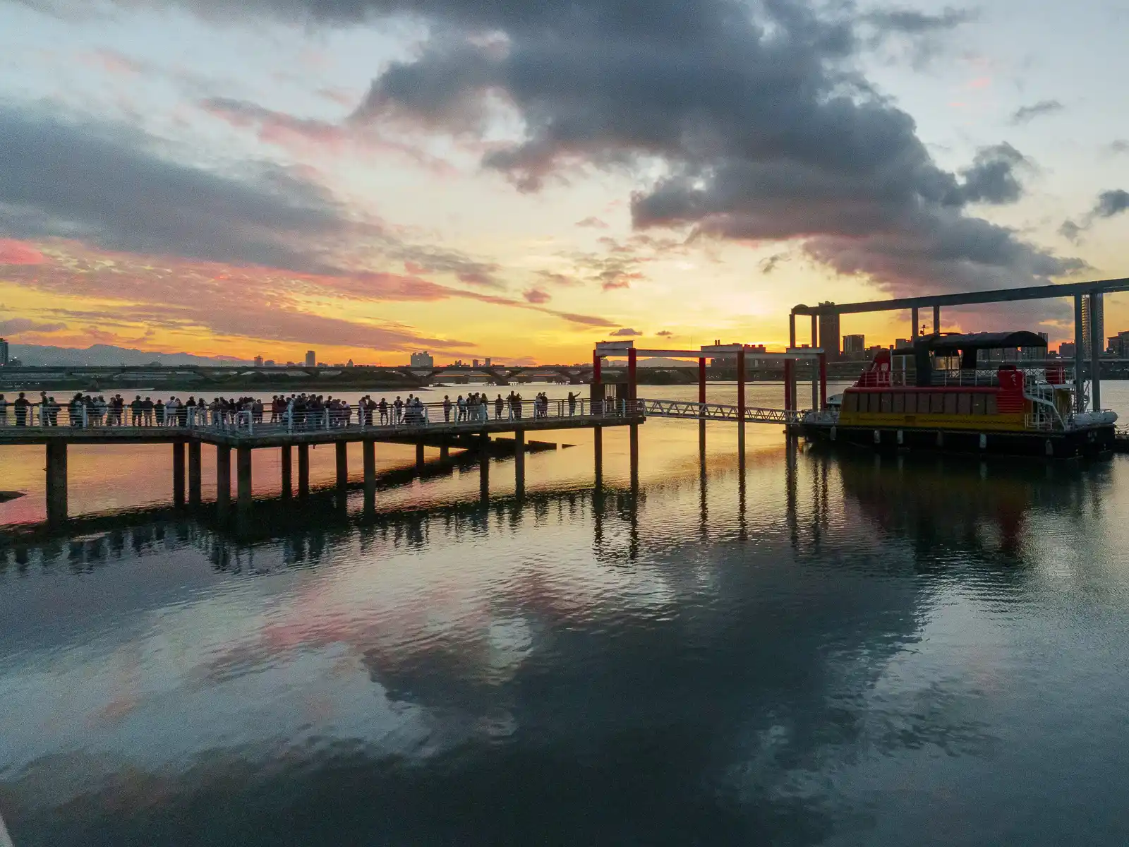 Sunset view over water with people on a pier.