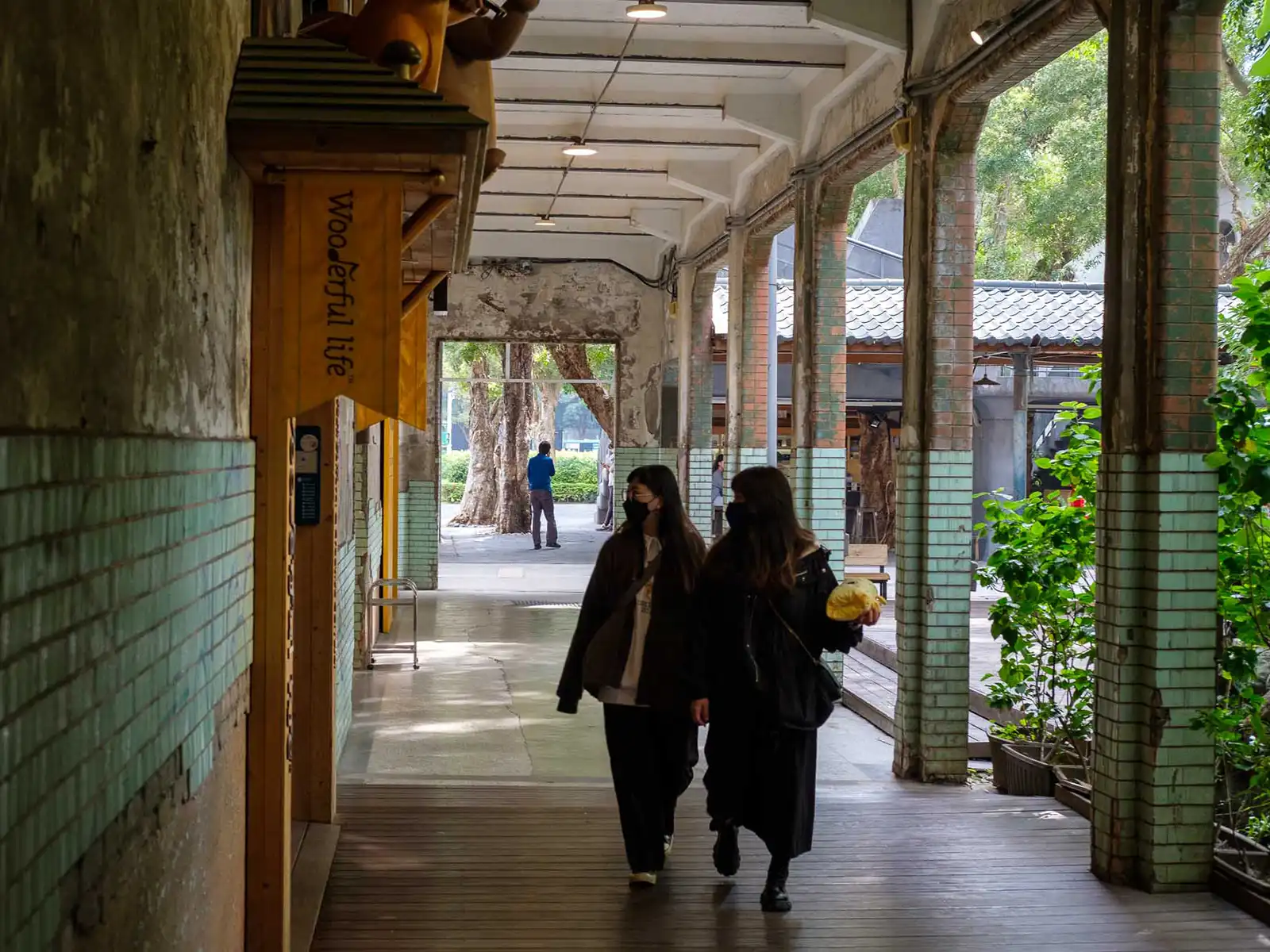 Two tourists walk under a covered path.