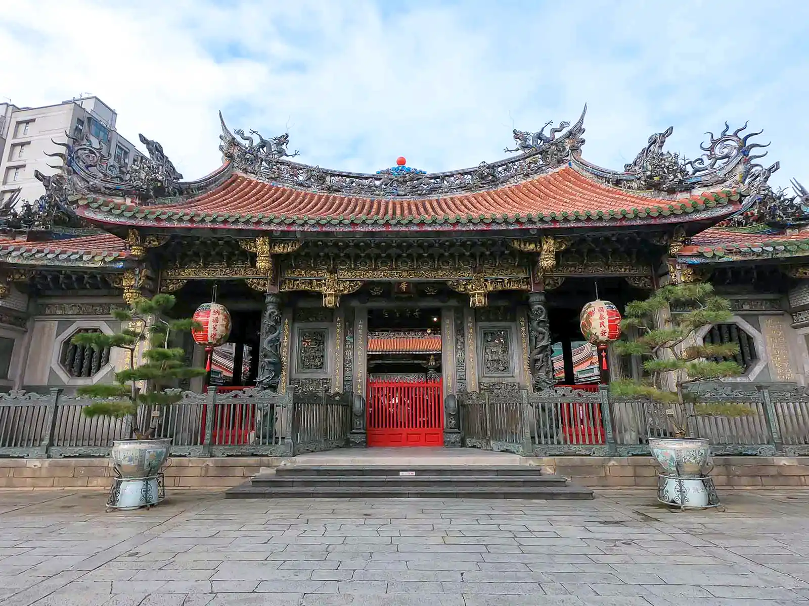 Front view of a temple wall with red lanterns.