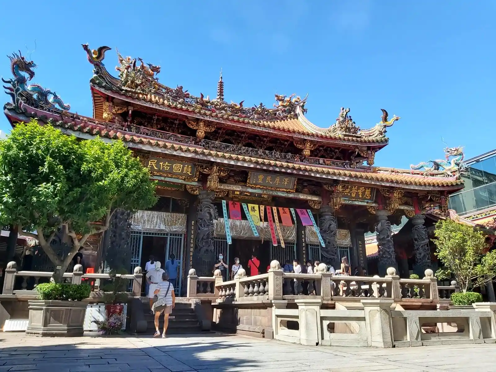 Temple entrance with visitors and greenery.