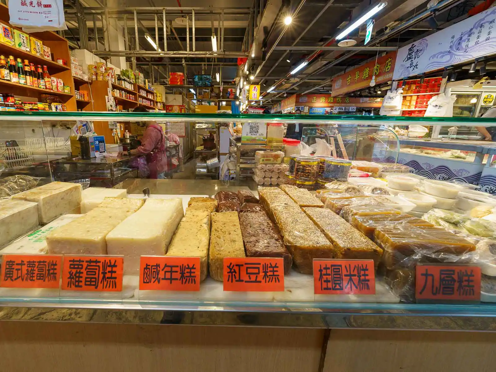 Shop displaying cakes made with various ingredients, including red breen and turnip, as well as preserved foods and sauces.