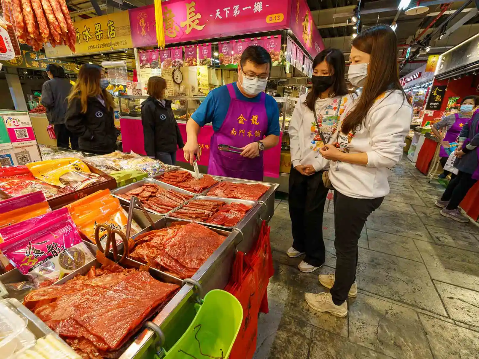 Vendor in aprons offers free jerky samples to customers.