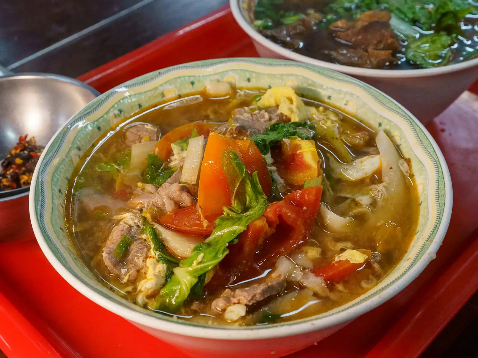 A bowl of hot, hearty soup with vegetables and meat.