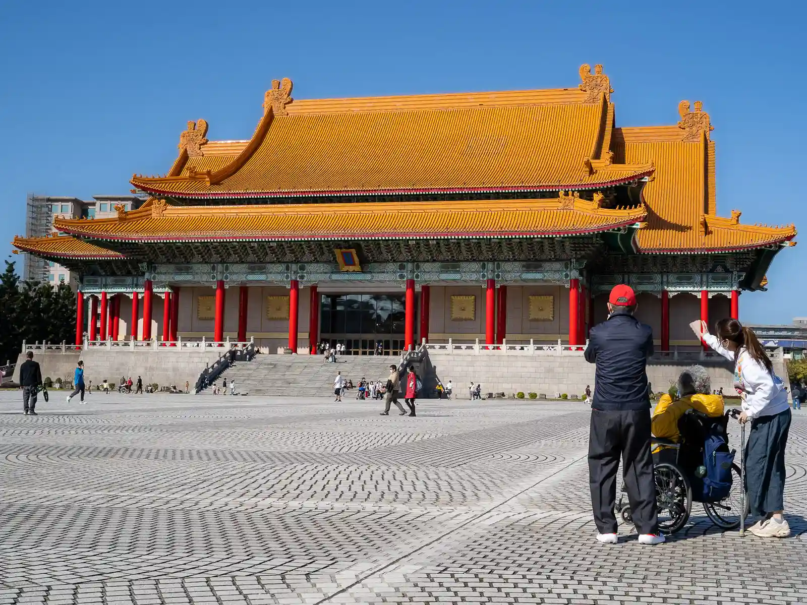 A traditional Chinese building with red columns and a long gold roof with red accents.