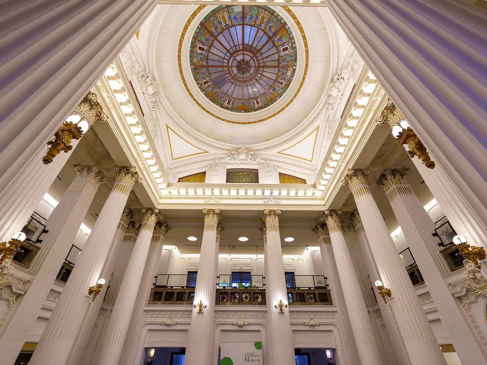 A lobby of the museum is surrounded by great white columns and a balcony.