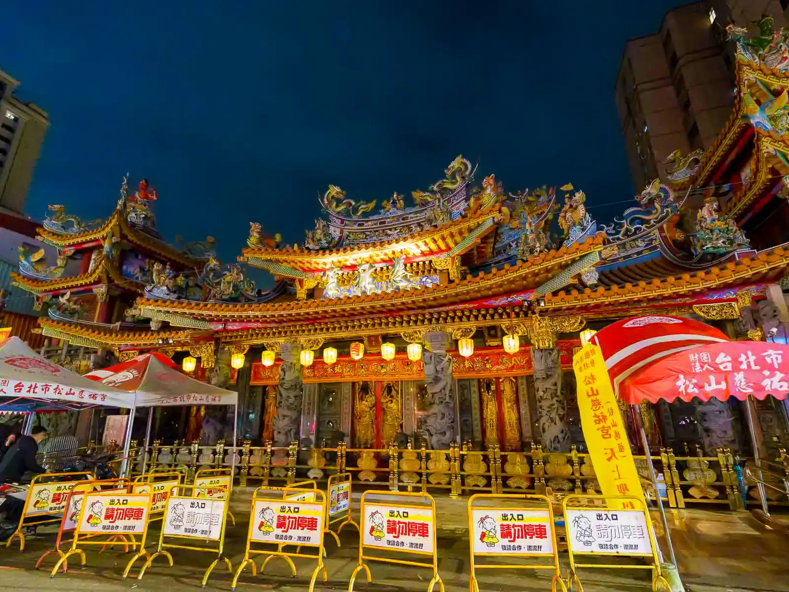 Ornate temple facade with intricate carvings and colorful decorations at night.