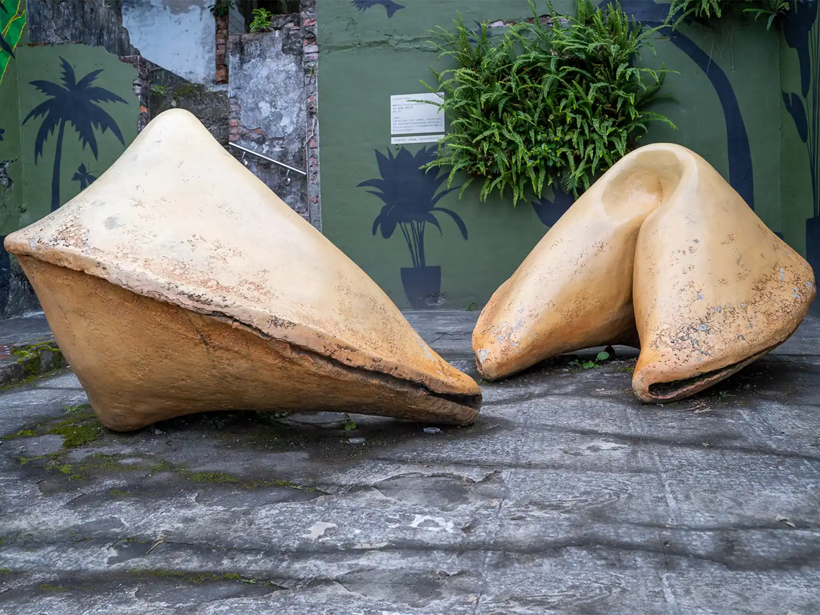 A large cement sculpture of two dumplings located in a small tiled outdoor area.