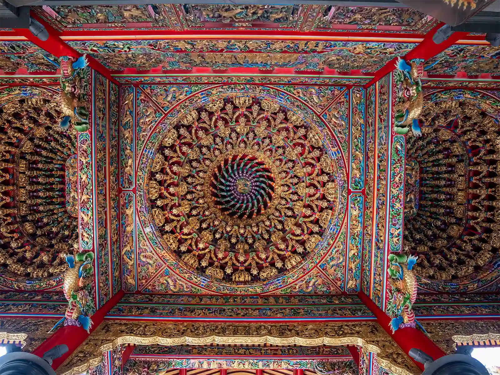 Intricate ceiling design featuring a complex array of sculptures and patterns in a temple.