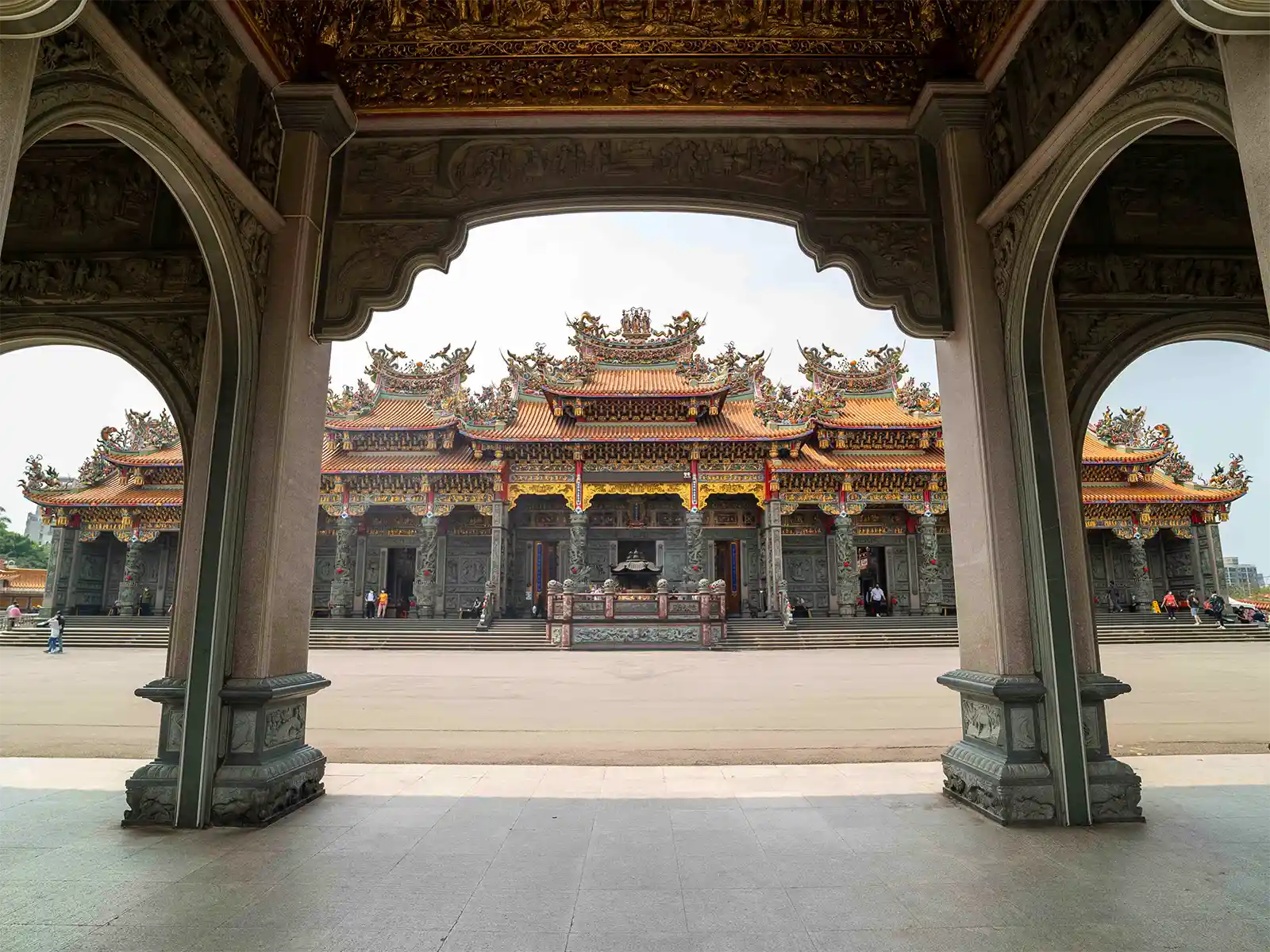 View of a grand temple through a large ornamental archway.