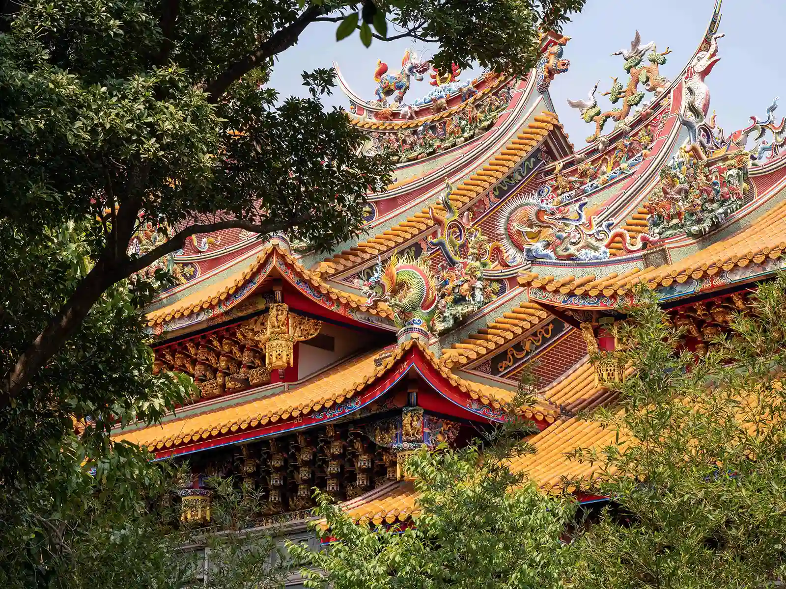 The elaborately decorated roof of the temple as seen through lush foliage.