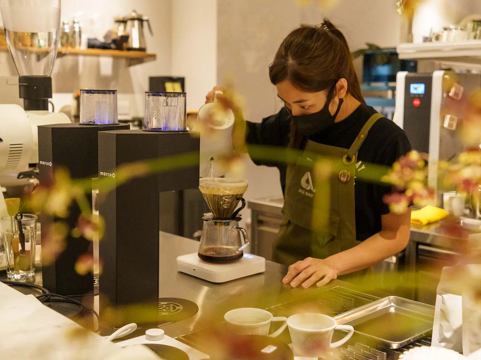 Barista carefully preparing a pour-over coffee at a minimalist coffee bar.