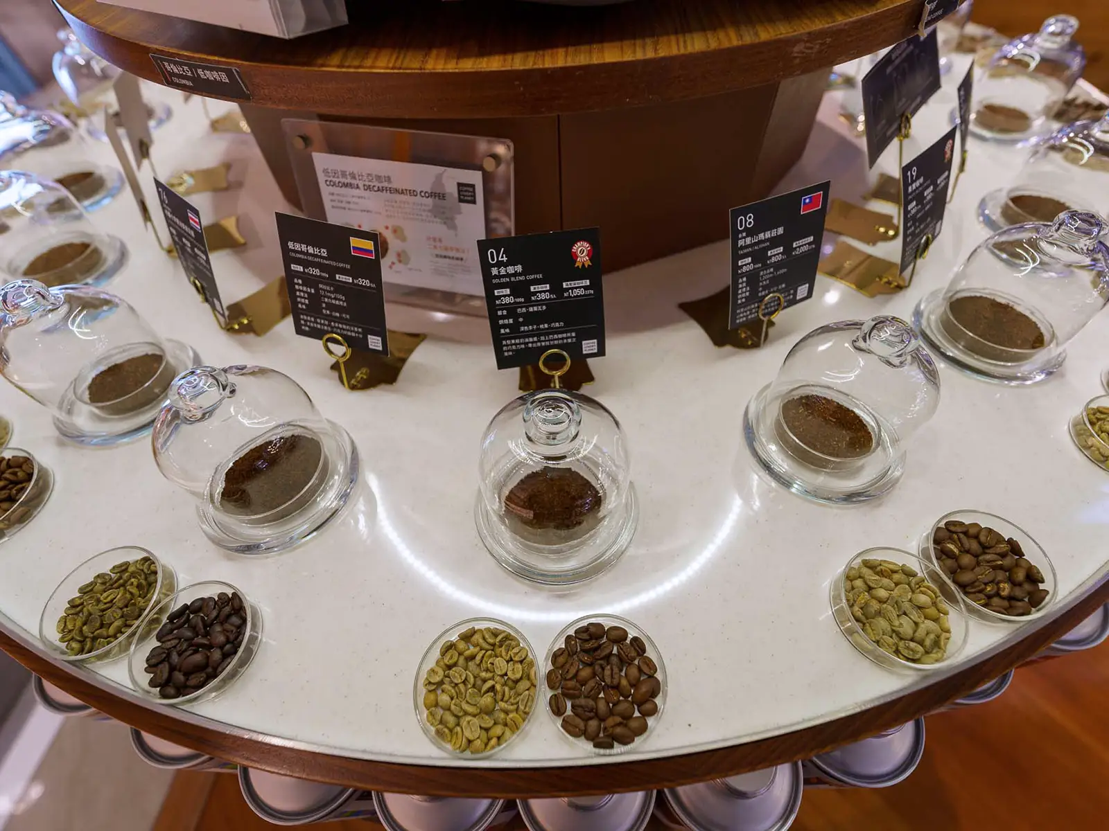 A display of various coffee beans and grounds in glass containers with labels.