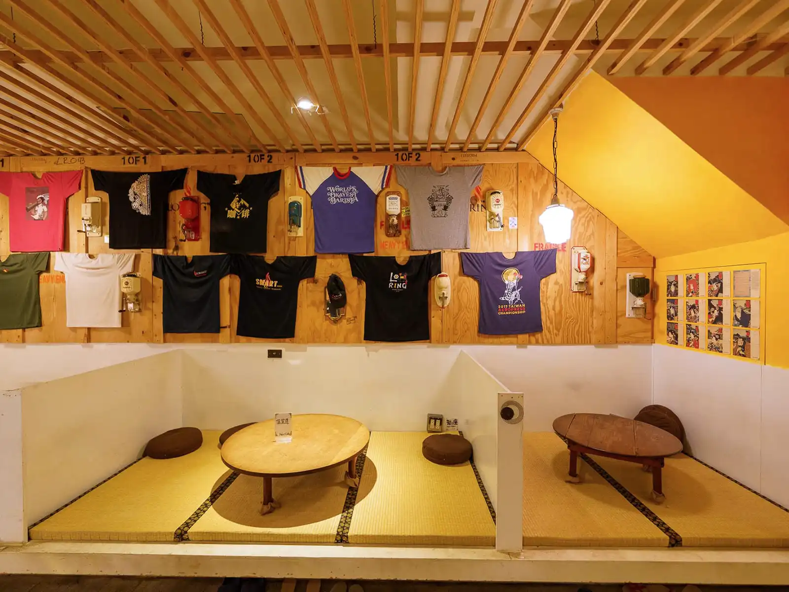 Cozy tatami seating area in a cafe with a vibrant display of t-shirts on the wall.