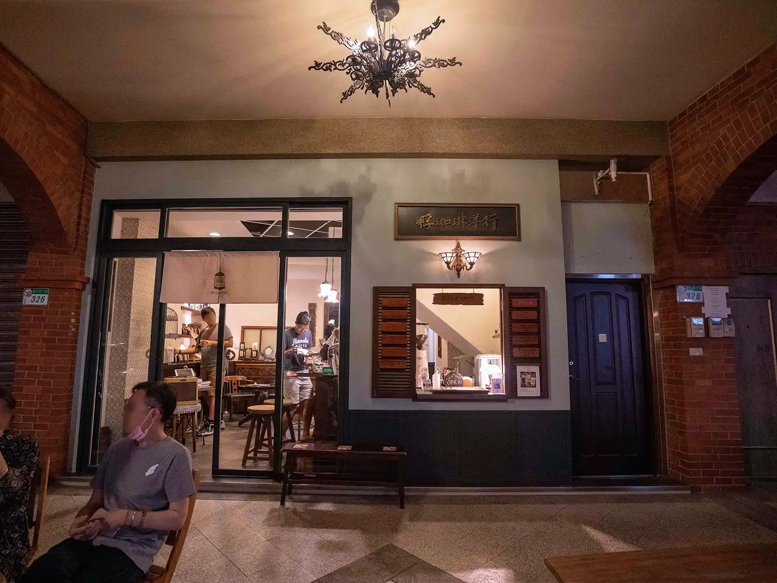 The exterior of a quaint Taipei cafe with patrons and warm lighting.